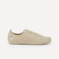 A light beige leather low-top barefoot dance sneaker with matching beige laces, shown in a side profile on a clean, light gray background.