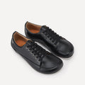 A pair of black leather lace-up barefoot dance sneakers  with black laces and silver eyelets, displayed on a clean off-white background.